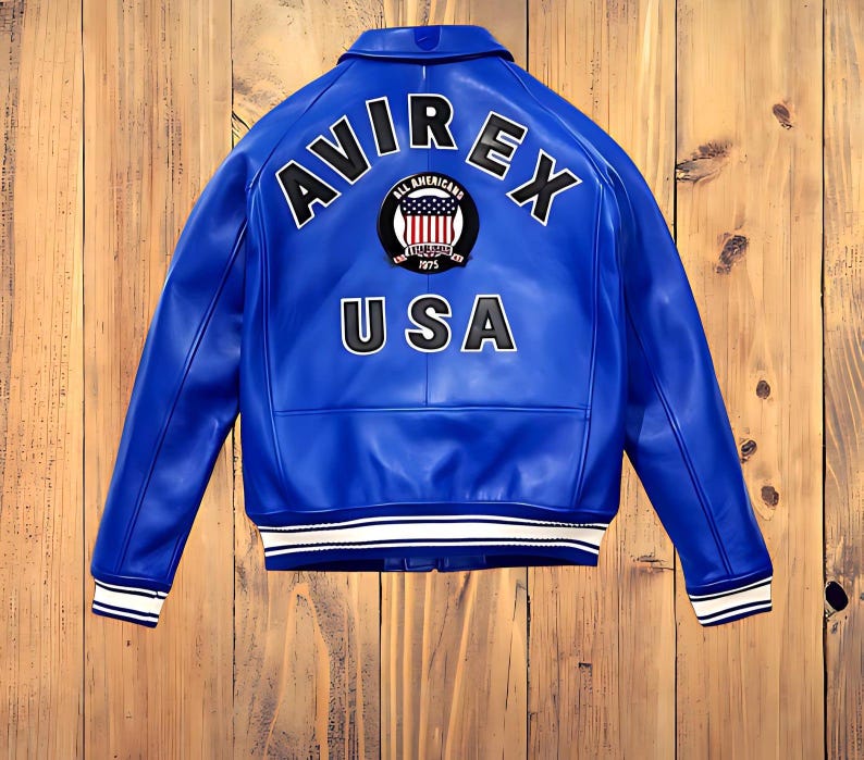 May include: A vibrant blue leather jacket with the word "AVIREX" arched across the shoulders, and "USA" below. The jacket features a patch with the words "ALL AMERICANS" and the year "1975". White stripes accent the cuffs and hem.