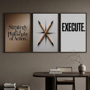 May include: A set of three framed wall art prints. The left print has a brown background with the black text "Strategy is a Philosophy of Action." The center print shows two crossed pencils on a white background. The right print has the black text "EXECUTE." on a white background.
