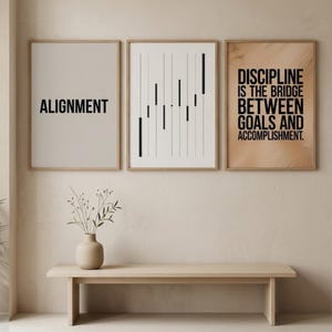 May include: Three framed prints with motivational quotes and abstract art. The first print says "ALIGNMENT" in black. The second has vertical black lines. The third reads "DISCIPLINE IS THE BRIDGE BETWEEN GOALS AND ACCOMPLISHMENT." A vase and bench are in the foreground.