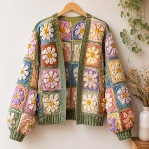 Peut inclure: Un cardigan à manches longues composé de carrés de crochet multicolores ornés de motifs de marguerites dans des tons jaune, rose, bleu et lavande. Le vêtement présente une bordure côtelée vert sauge sur l'ouverture avant, les poignets et l'ourlet.