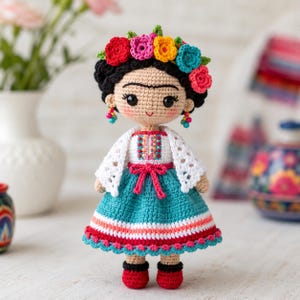 May include: A handcrafted crochet doll featuring black hair styled with a vibrant floral crown of red, pink, yellow, and blue flowers. The doll wears a white top with colorful embroidery, a teal skirt with red and white stripes, and red shoes.