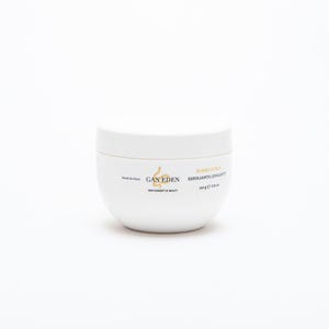 Può includere: Un barattolo bianco e arrotondato di Burro Scrub, un prodotto esfoliante. Il barattolo ha un coperchio e presenta il marchio "GAN EDEN" e il testo "NEW CONCEPT OF BEAUTY". L'etichetta indica anche che il prodotto è fatto in Italia e contiene 190 g.