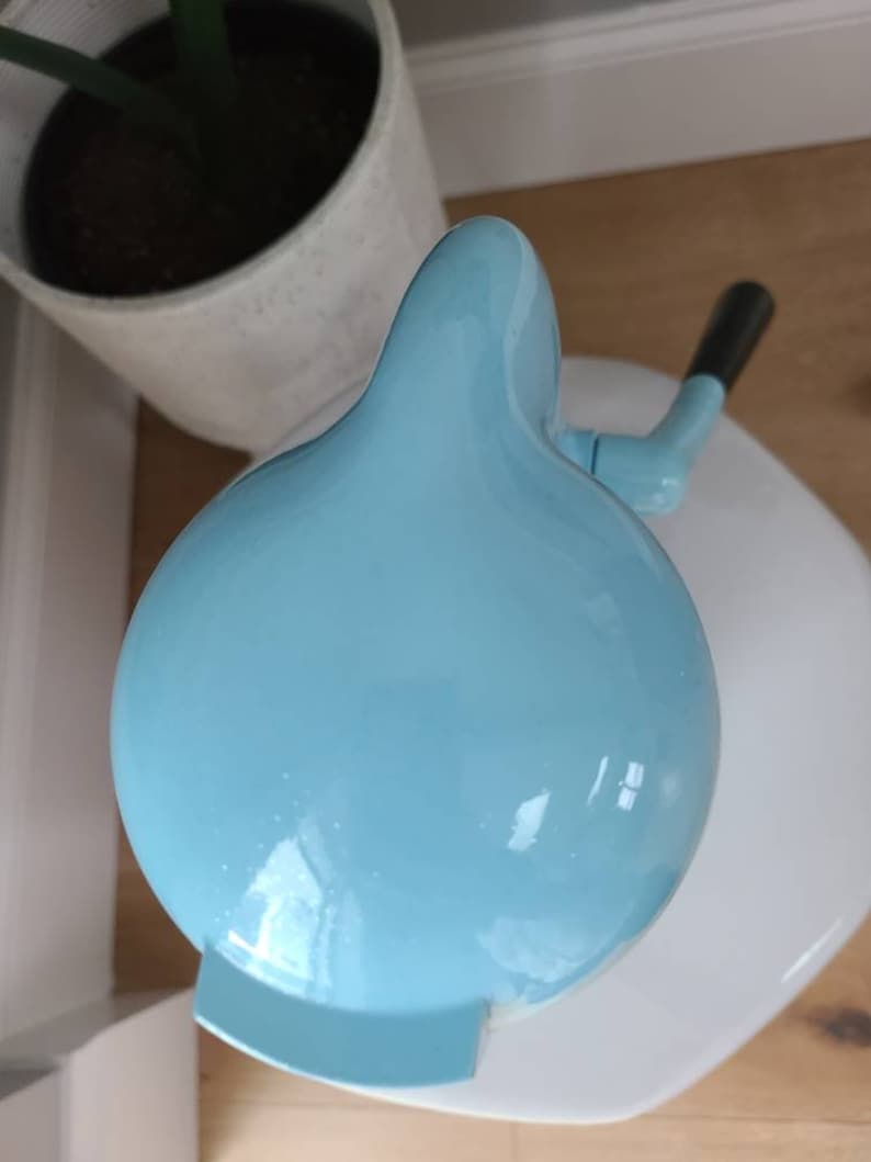 Puede incluir: Una m&aacute;quina de hacer helados de color azul claro con una base blanca y un asa. La m&aacute;quina de hacer helados tiene forma de c&uacute;pula y un acabado liso y brillante.