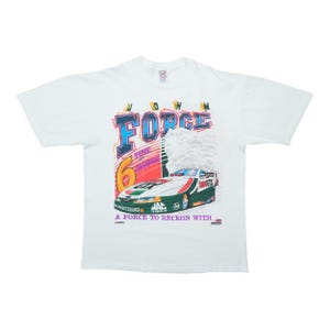May include: A white short-sleeve t-shirt featuring a graphic of a green, white, and red race car with the text FORCE, the number 6, and the phrase A FORCE TO RECKON WITH. The design includes colorful lettering and smoke effects above the car.