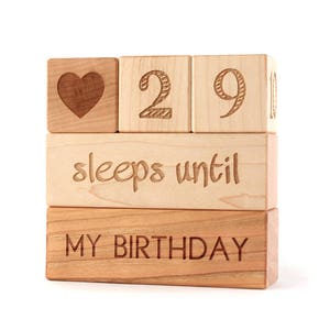 May include: Wooden blocks stacked to spell "29 sleeps until my birthday" with a heart symbol on the top block.