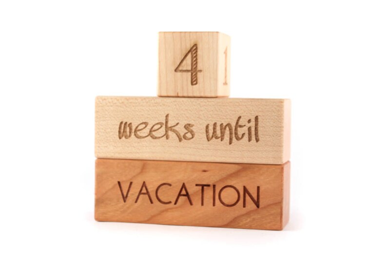 May include: Wooden blocks stacked to count down the weeks until vacation. The top block reads "4" and the middle block reads "weeks until". The bottom block reads "VACATION".