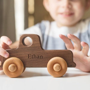 K&ouml;nnte beinhalten: Ein h&ouml;lzerner Spielzeug-LKW mit brauner Oberfl&auml;che und R&auml;dern aus Naturholz. Der LKW ist mit dem Namen "Ethan" personalisiert, der auf die Seite graviert ist.