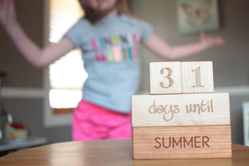 May include: Wooden blocks stacked to count down the days until summer. The top block reads "31 days until summer".