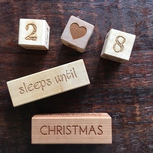 May include: Wooden blocks spelling out "28 sleeps until Christmas". The blocks are natural wood with brown lettering.