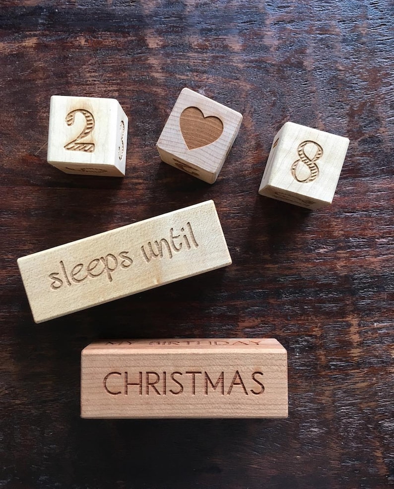 May include: Wooden blocks spelling out "28 sleeps until Christmas". The blocks are natural wood with brown lettering.