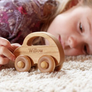 Pode incluir: Um carro de brinquedo de madeira com o nome "Willow" gravado na lateral. O carro &eacute; feito de madeira clara e tem um formato cl&aacute;ssico com quatro rodas redondas. O brinquedo &eacute; projetado para crian&ccedil;as.