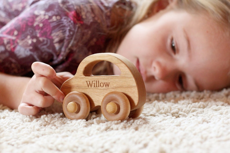 Pode incluir: Um carro de brinquedo de madeira com o nome "Willow" gravado na lateral. O carro &eacute; feito de madeira clara e tem um formato cl&aacute;ssico com quatro rodas redondas. O brinquedo &eacute; projetado para crian&ccedil;as.