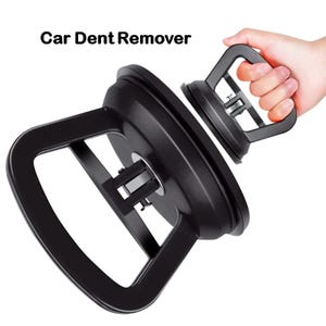 Puede incluir: Extractor de abolladuras de coche negro con asa. El texto "Car Dent Remover" está impreso en negro. La herramienta está diseñada para sacar abolladuras de los vehículos.