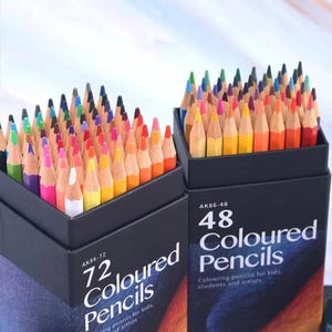 Peut inclure: Deux boîtes rectangulaires noires remplies de crayons de couleur taillés. La boîte de gauche est étiquetée AK86-72 72 Coloured Pencils, et la boîte de droite est étiquetée AK86-48 48 Coloured Pencils. Les crayons présentent un large spectre.
