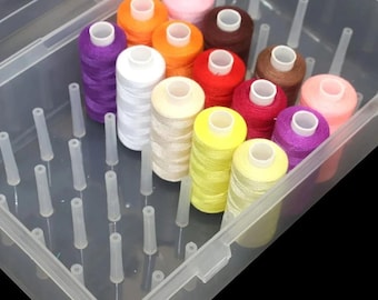 May include: A clear plastic storage box containing multiple spools of sewing thread in various colors including purple, white, orange, yellow, red, brown, and pink. The container features upright pegs designed to hold each individual spool securely.