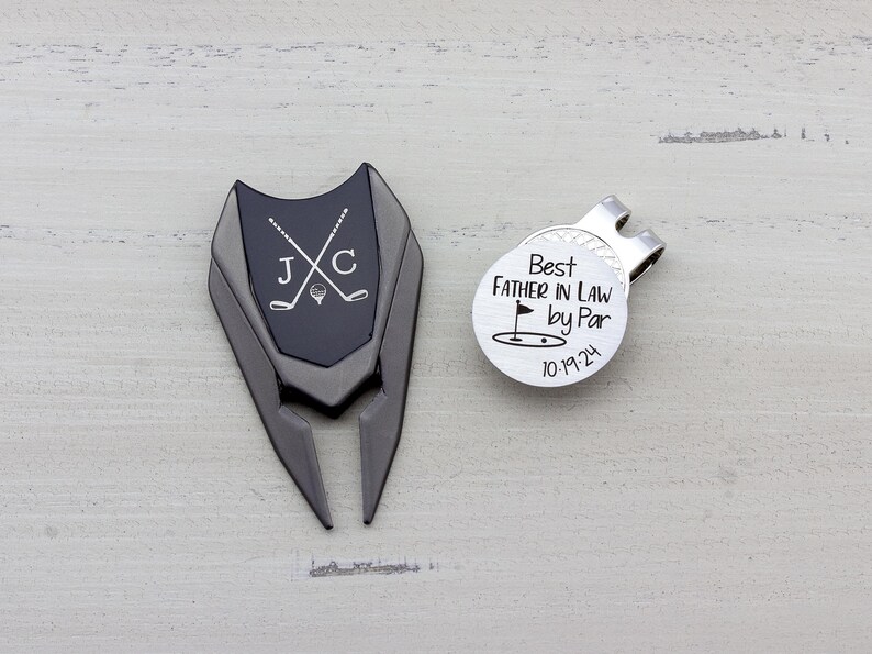gunmetal color metal divot tool with black metal divot tool ball marker personalized with crossed clubs with initials on each side. Silver stainless steel golf marker engraved best father in law by par with golf flag graphic and date.