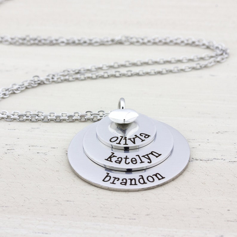 3 layer stainless steel disc necklace with kids name on each layer with a sterling silver heart charm on top.