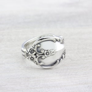 May include: A silver spoon ring with floral details. The ring is made from a vintage spoon and has a unique, handcrafted look.