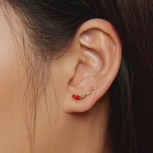 May include: Gold-coloured koi fish earrings with red enamel detailing. The earrings are designed to be worn on the ear. The earrings are a unique and stylish accessory.