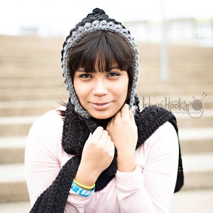 Puede incluir: Una persona joven con un gorro de punto gris y negro con una bufanda a juego. El gorro tiene una punta puntiaguda y la bufanda está envuelta alrededor del cuello y los hombros.