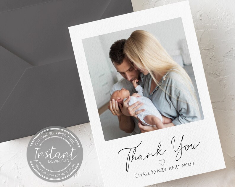 May include: White thank you card with a photo of a couple holding a newborn baby. The card features the words "Thank You" in elegant script, with the names "Chad, Kenzy, and Milo" below. A gray envelope is visible in the background.