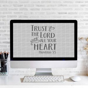 Może przedstawiać: Komputer stacjonarny wyświetla tekst "Trust in the Lord with all your heart Proverbs 3:5" czarną czcionką na szarym tle w kratkę. Na białym biurku znajdują się klawiatura, mysz, oł&oacute;wki i czarny kubek.