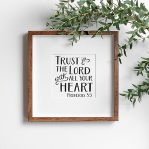 Może przedstawiać: Kwadratowy oprawiony wydruk z napisem "Trust in the Lord with all your heart" czarnym pismem. Rama ma ciepły brązowy kolor, a nadruk jest umieszczony na białym passe-partout. Zieleń jest ułożona w prawym g&oacute;rnym rogu.