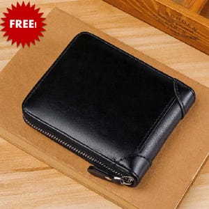 May include: A black leather wallet with a zipper closure. The wallet is rectangular and appears to be made of smooth leather. The word "FREE!" is in a red starburst in the upper left corner.
