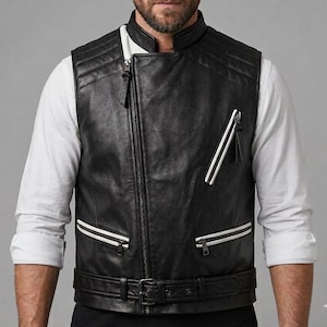 May include: Black leather vest with a quilted design on the shoulders. The vest features a diagonal zipper, white stripes, and a belt with a buckle. The vest is worn over a white long-sleeve shirt.