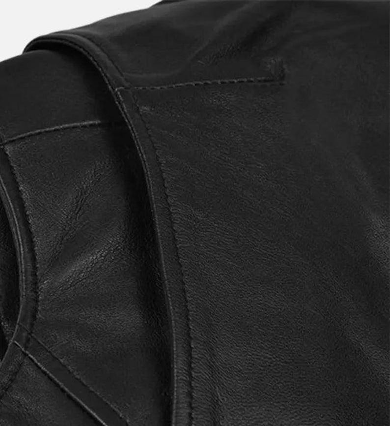 May include: Close-up of a black leather jacket, showcasing the texture and stitching details. The image highlights the shoulder and upper chest area, emphasizing the quality of the material and craftsmanship. The jacket appears to be a classic style.