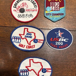 May include: A selection of bowling patches with different designs and text. The patches display bowling pins, bowling balls, and text including "Greater Gulf Coast 200 Game" and "USBC 200 Game Award". The patches are in various shapes and colours.