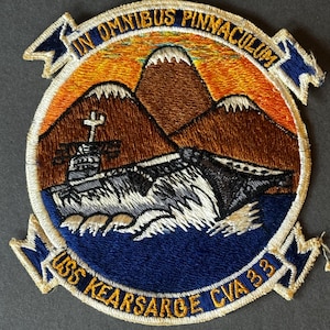 Könnte beinhalten: Gestickter Aufnäher mit einem Marineflugzeugträger, Bergen und dem Text "IN OMNIBUS PINNACULUM" und "USS KEARSARGE CVA 33". Der Aufnäher hat ein blaues, orangefarbenes, braunes und weißes Farbschema.