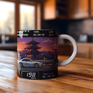 May include: White ceramic mug featuring a pixelated image of a car racing past a Japanese pagoda at sunset. The mug displays the text "198 KM/H" and other racing data. The mug has a white handle.