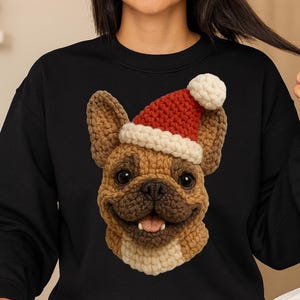 Puede incluir: Sudadera negra con un Bulldog Francés tejido a ganchillo con un gorro de Papá Noel. La cara del perro está detallada con hilo marrón, beige y crema, con un gorro rojo y blanco. El perro está sonriendo.