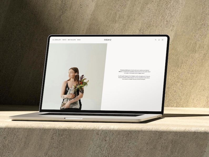 Puede incluir: Un port&aacute;til plateado muestra un sitio web con una mujer sosteniendo flores. El sitio web presenta el logotipo "MUSE" y texto sobre Florence Ellison. El port&aacute;til est&aacute; sobre una superficie clara con un fondo texturizado.