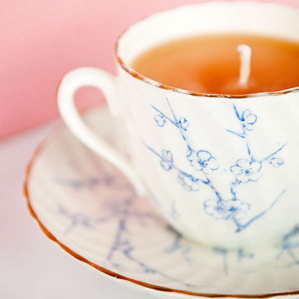 Fleurs blanches et bleues sur les rameaux, bougie de tasse de thé vintage et soucoupe. lumière teacup thème printemps