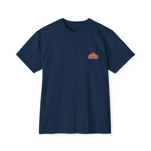 May include: Navy blue short-sleeved t-shirt with a chest pocket. The pocket features a red and white graphic of a barn with the text "Farm Tough Outfitters". The shirt is made of a soft, comfortable material.