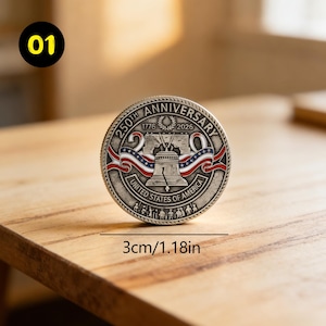 May include: A silver coin commemorating the 250th anniversary of the United States, with the years 1776 and 2026. The coin features the Liberty Bell, red, white, and blue ribbons, and the text "United States of America". The coin is 1.18 inches in diameter.