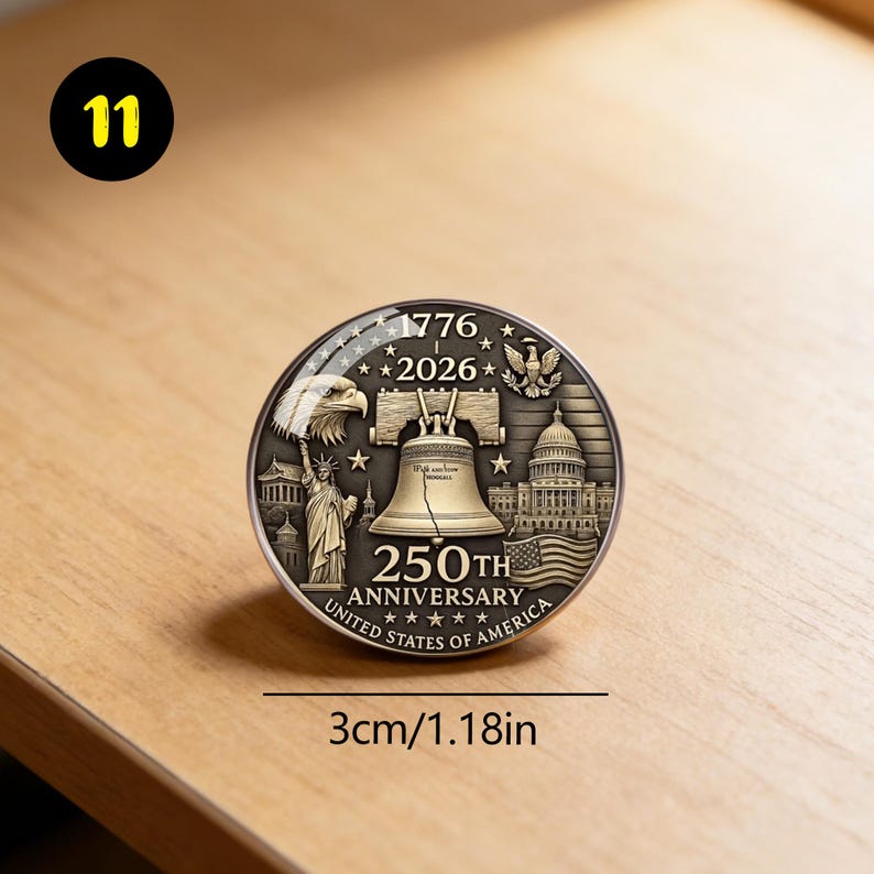 May include: A round, silver-colored commemorative coin with the text "1776-2026" and "250th Anniversary United States of America." The coin features the Liberty Bell, an eagle, the Statue of Liberty, and the Capitol building. The coin is 1.18 inches in diameter.