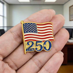 May include: A gold-colored pin featuring a waving American flag with red and white stripes and a blue field of stars. The number "250" in blue and the year "1776" are below the flag, commemorating a historical event.