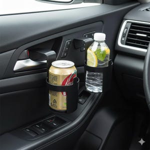 Puede incluir: Soportes negros para vasos en la puerta del coche que sostienen una lata de refresco y una botella de agua con rodajas de limón. Los soportes están montados en el panel de la puerta, cerca de la manija y los controles de las ventanas.