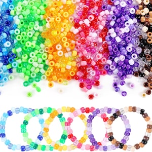 May include: A selection of colourful plastic beads in shades of blue, green, yellow, orange, red, pink, purple, brown, and clear. Several beaded bracelets are shown at the bottom, demonstrating the beads' use in jewellery making.