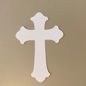 May include: A white paper cross with a simple, traditional design. The cross is cut out of paper and has a smooth, matte finish.