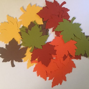 May include: A pile of paper fall leaves in various shades of red, orange, yellow, and green. The leaves are cut out in the shape of maple leaves.