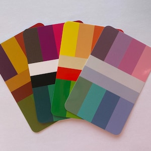 May include: A collection of five color palette cards, each displaying a unique arrangement of rectangular color blocks. The cards showcase a variety of hues, including shades of yellow, green, purple, and pink, arranged in vertical and horizontal patterns.