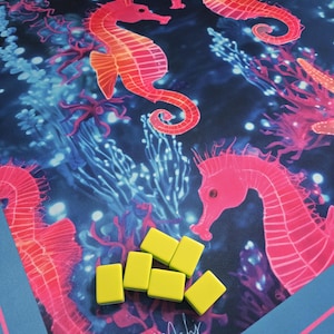 May include: A game board featuring a vibrant underwater scene with pink seahorses and coral against a dark blue background. Six yellow game tiles are scattered on the board. The text "Beachy Mahj" is in the lower left corner.