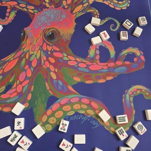 May include: A blue Mahjong game mat featuring a colorful, psychedelic octopus design. White Mahjong tiles are scattered around the mat. The mat has the text "BeachyMary" in the lower right corner.