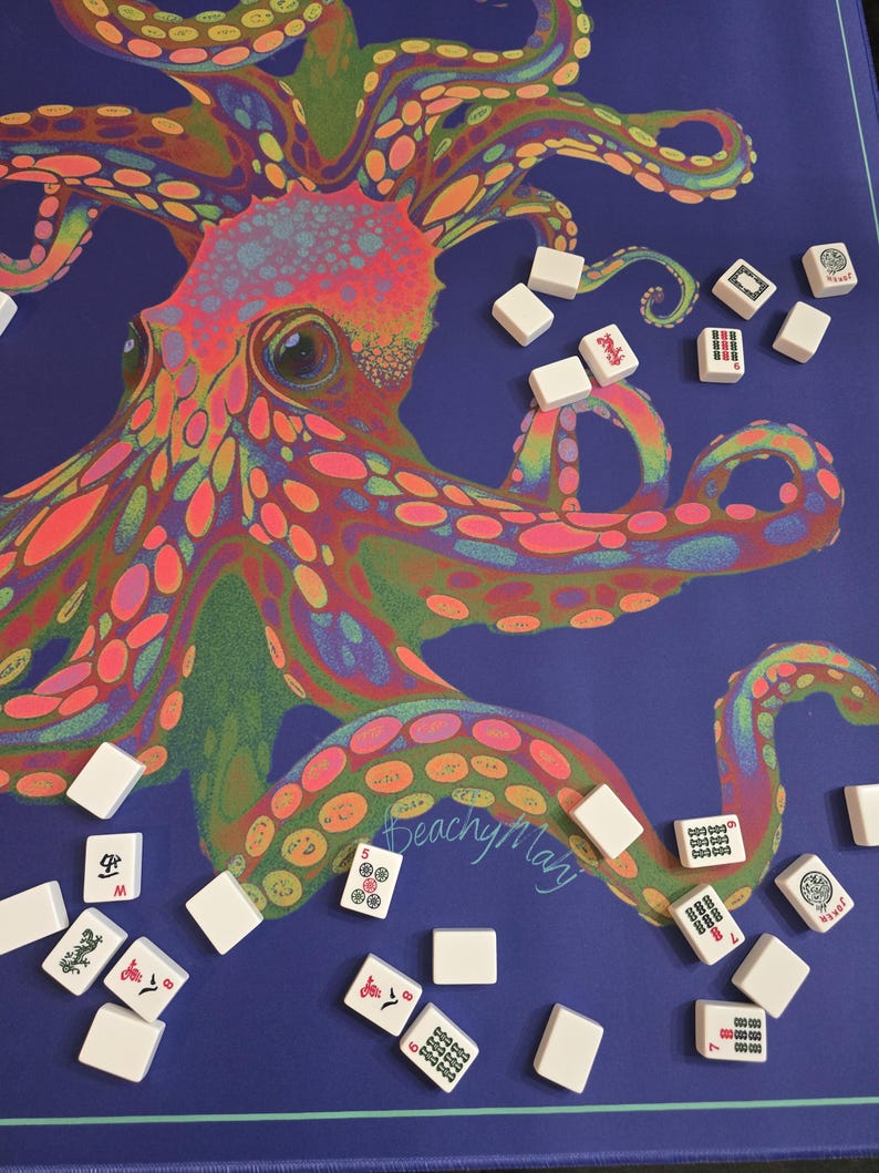 May include: A blue Mahjong game mat featuring a colorful, psychedelic octopus design. White Mahjong tiles are scattered around the mat. The mat has the text "BeachyMary" in the lower right corner.
