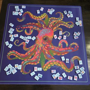 May include: A purple Mahjong game mat featuring a colorful octopus design. The octopus is rendered in vibrant hues of orange, pink, green, and yellow. White Mahjong tiles are scattered around the mat, ready for play. The mat has a light green border.