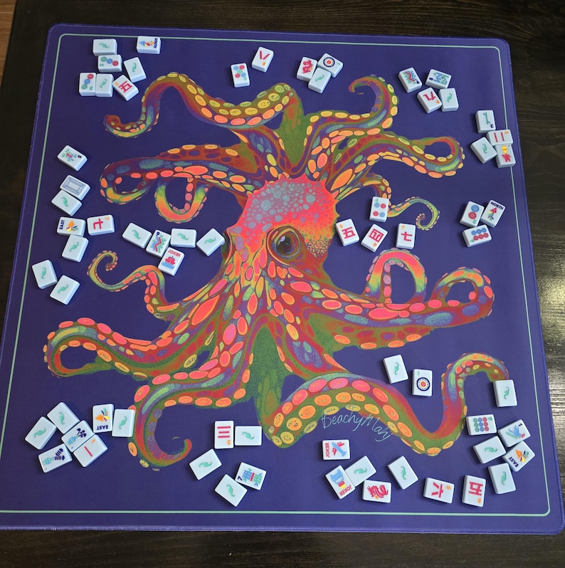 May include: A purple Mahjong game mat featuring a colorful octopus design. The octopus is rendered in vibrant hues of orange, pink, green, and yellow. White Mahjong tiles are scattered around the mat, ready for play. The mat has a light green border.
